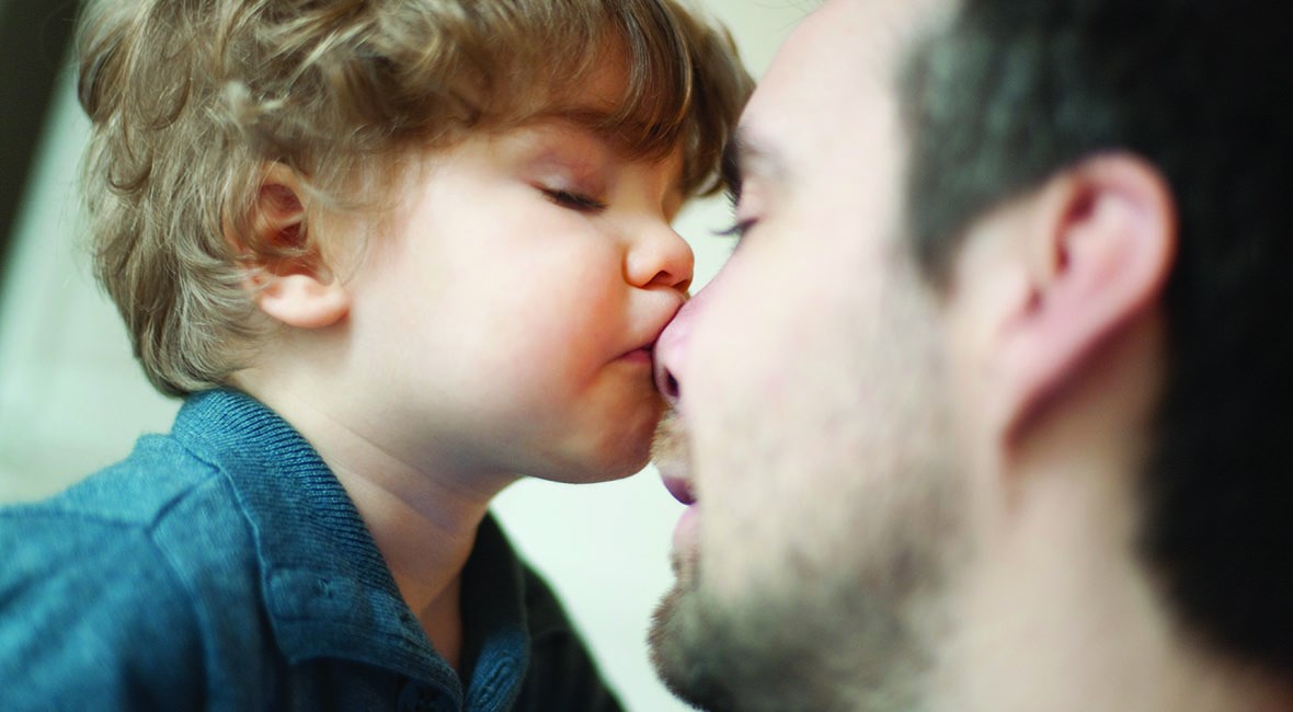 boy kissing father on the nose